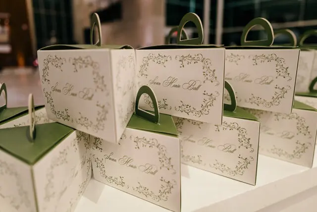 White boxes with green floral trim and 'Swan House Ball' text