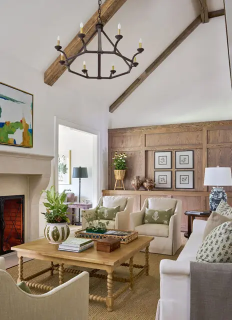 Living room with vaulted ceiling, exposed beams, fireplace, and wood paneled wall.