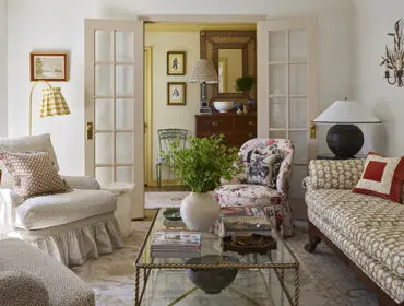 Living room with floral armchair, patterned sofa, and glass coffee table.