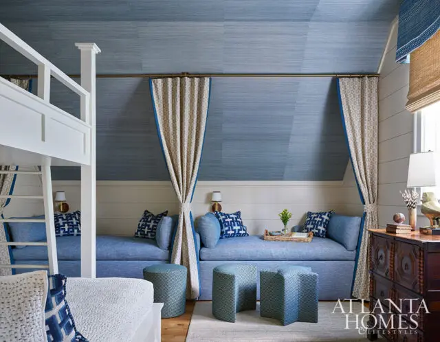 Blue daybeds with patterned pillows and curtains, bunk bed, and wooden dresser.