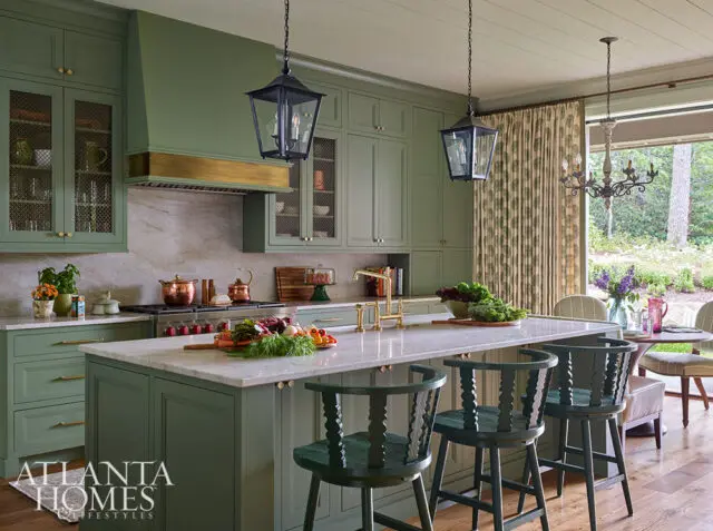Sage green kitchen with marble island, brass faucet, and pendant lights.
