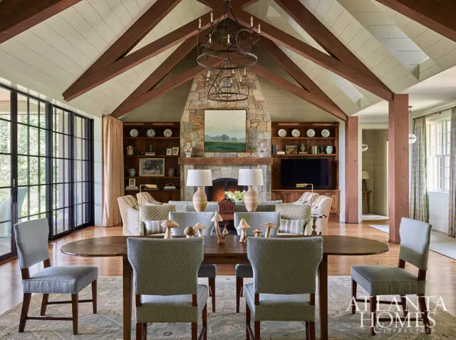 Living room with vaulted wood beam ceiling, stone fireplace, and dining area.