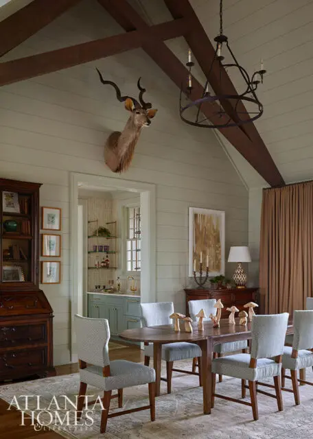 Dining room with taxidermy kudu head, wood beams, and mushroom decor on table