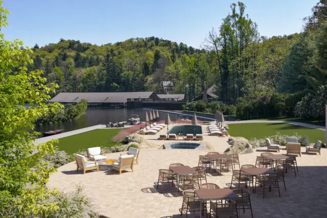 Boathouse on a lake with a pool, lounge chairs, and outdoor dining area.
