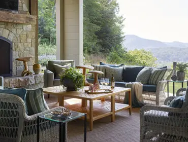 Covered porch with stone fireplace, wicker seating, and mountain view