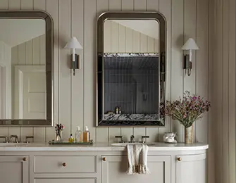Neutral bathroom with double vanity, paneled walls, and two framed mirrors.