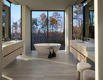Modern bathroom with freestanding tub, dual vanities, and large windows overlooking trees