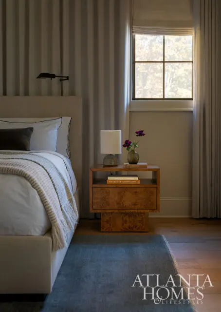 Bedroom with upholstered bed, burl wood nightstand, and window.