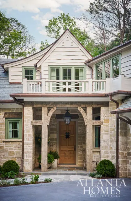 White clapboard house with stone foundation and green windows.