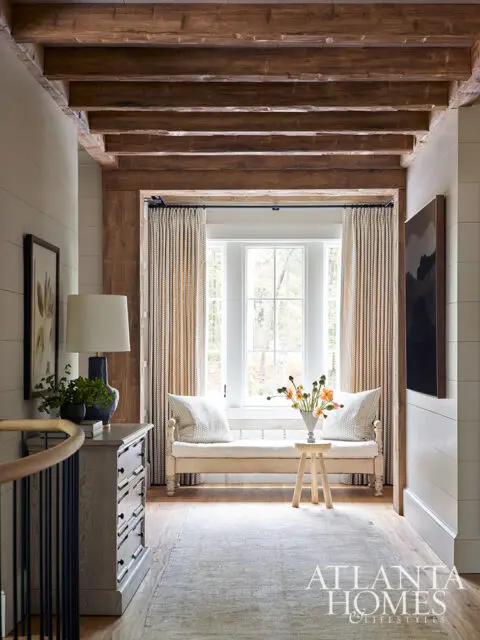 Hallway with exposed wooden beams, window seat, and built-in cabinetry.