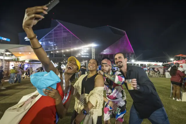 Four friends taking a selfie at night with a stadium in the background