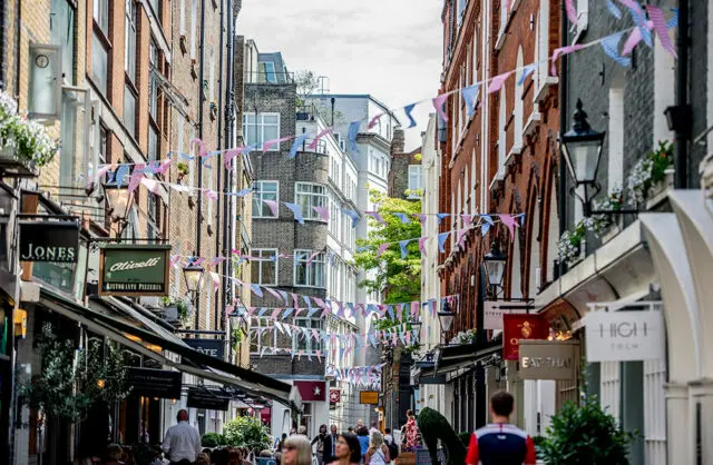 Street with buildings, shops, and bunting flags overhead.
