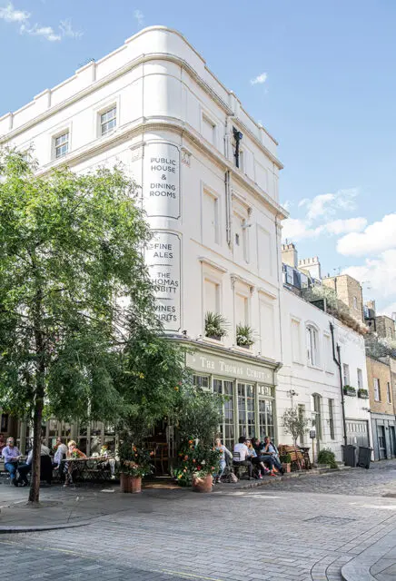 White building with "The Thomas Cubitt Public House & Dining Rooms" signage. Outdoor seating with