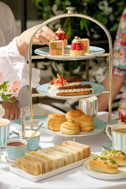 Tiered stand with finger sandwiches, scones, eclairs, and small cakes