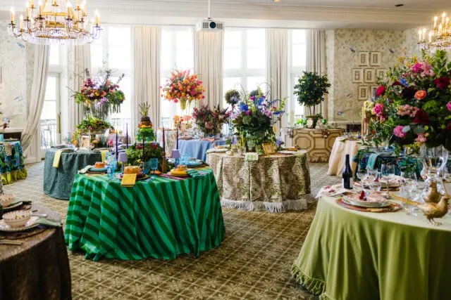 Elegant room with floral arrangements, striped tables, and a chandelier.