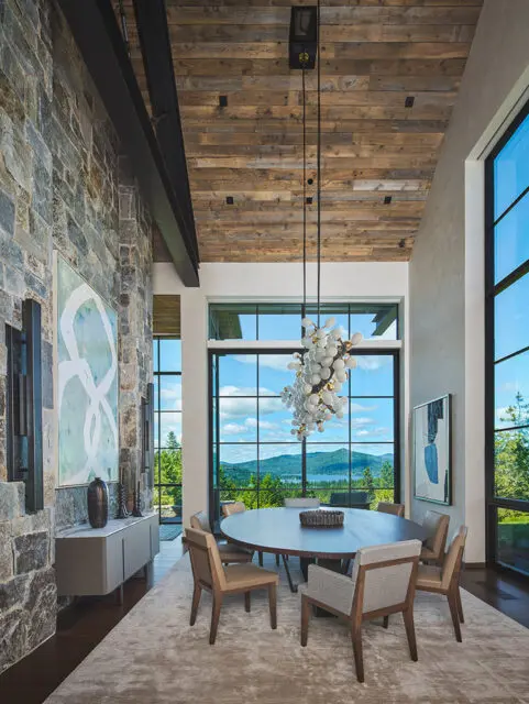 Stone wall, wooden ceiling, and a large dining table with a chandelier.