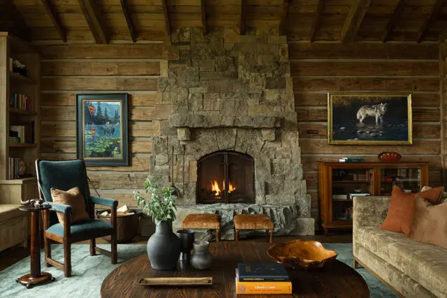 Rustic stone fireplace with wooden logs and artwork in a reading room.