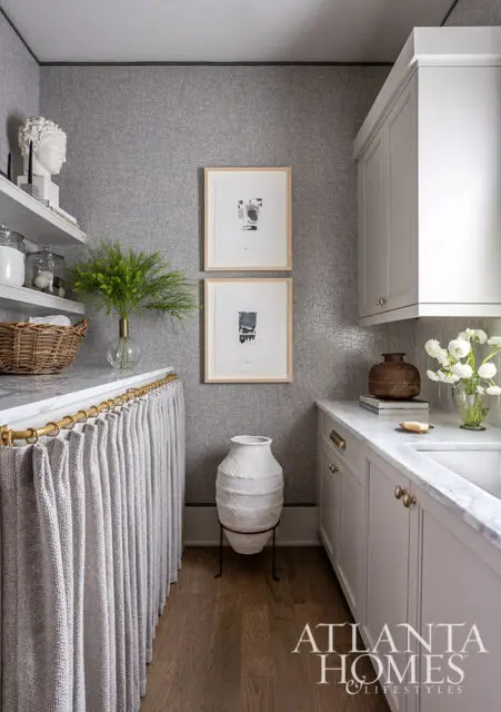 White laundry room with marble countertop, open shelving, and textured gray wallpaper.