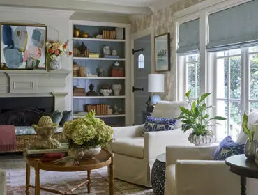 Living room with fireplace, built-in bookshelves, and large windows overlooking a garden.