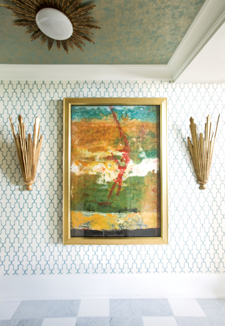 Hallway with teal and gold textured ceiling, geometric patterned wallpaper, abstract painting in gold frame, and gold sunburst sconces.