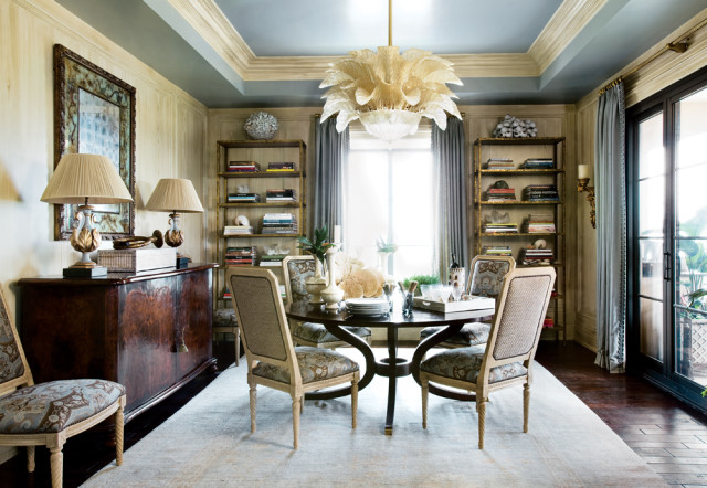 Dining room with a dark wood table and chairs upholstered in patterned fabric, a burl wood buffet, and a large glass chandelier.