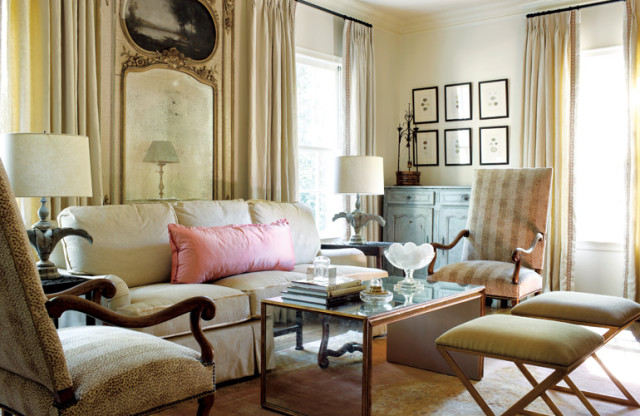 Living room with a cream sofa, a mirrored coffee table, upholstered chairs with animal print and striped fabric, and a distressed blue cabinet