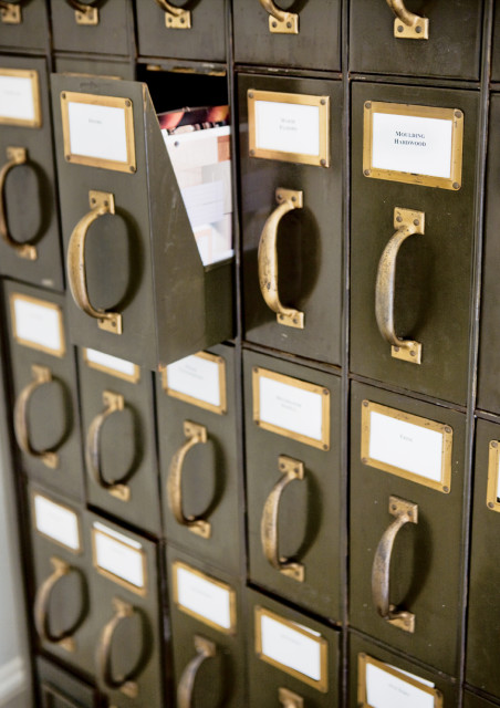 Close-up of a vintage metal filing cabinet with brass handles and labels, one drawer is open revealing samples.