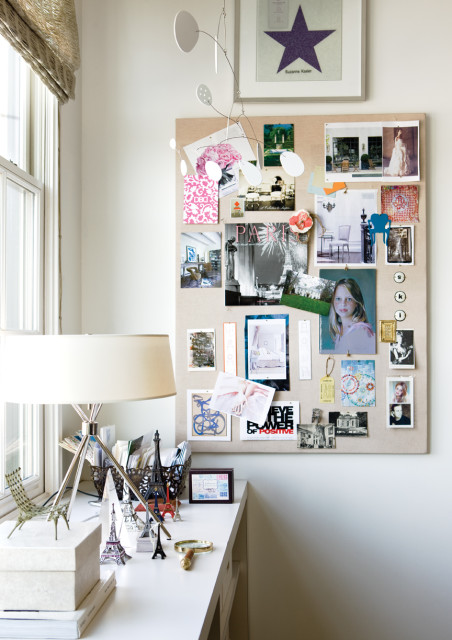 Desk with a lamp, Eiffel Tower miniatures, and a corkboard covered in images, magazine clippings, and a framed purple star signed Suzanne Kasler.