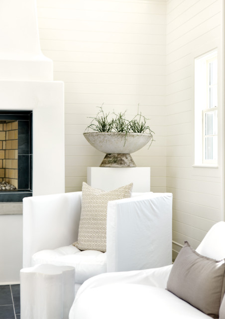 Living room with white slipcovered sofas, a modern white fireplace, and a large concrete planter with greenery.