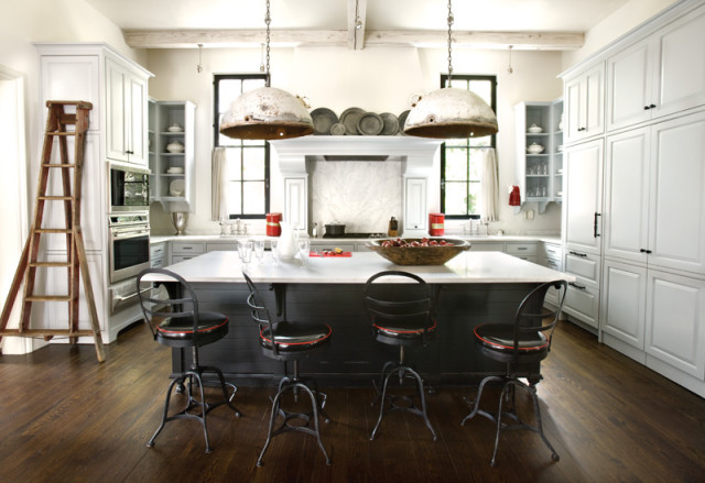 Farmhouse kitchen with white cabinetry, dark island with marble countertop, industrial pendant lights, and a vintage wooden ladder.