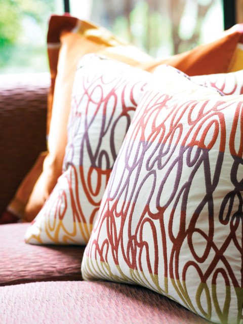 Close-up of throw pillows with a white background and a swirling pattern in red, purple, and yellow