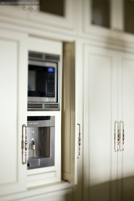Cream kitchen cabinetry with integrated microwave and coffee maker, featuring ornate silver handles.