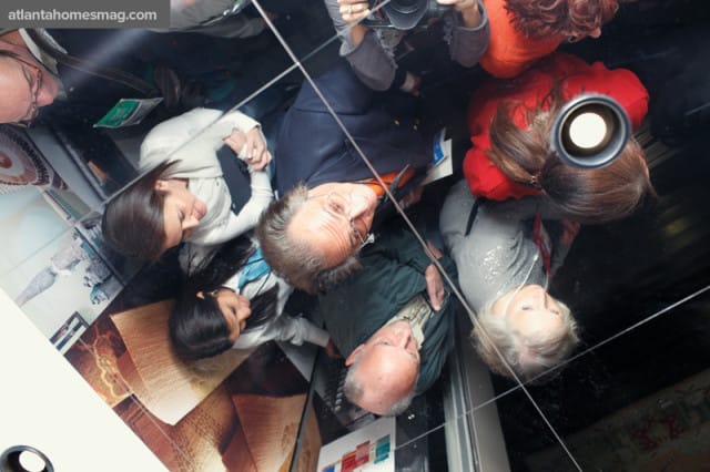 Reflection of a group of people in a mirrored ceiling, with the website URL atlantahomesmag.com visible in the upper left corner.