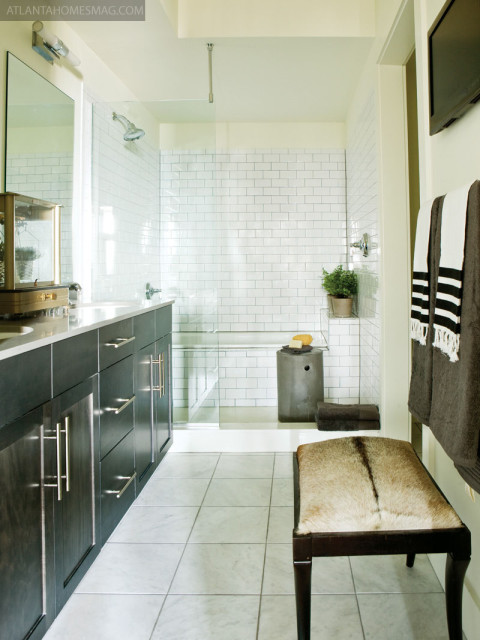 In Atlanta, the guest bathroom packs maximum impact thanks to inky black walls, submarine-light sconces and artwork by Todd Murphy, available through Astolfi Art. In the same unit, the master bathroom is at once sleek and cozy, an inviting hide bench helping to enhance this effect.