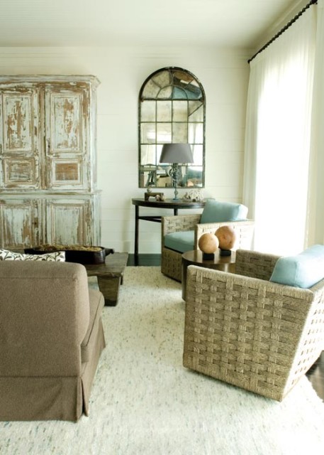 In the living room, a cabinet-turned-entertainment unit wears its peeling paint like a badge of honor. Flanking the piece is a pair of French windows that designer Carter Kay fitted with an antique mirror.