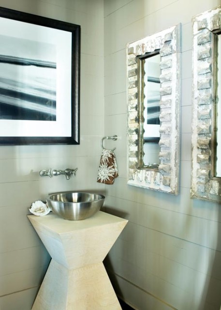 In lieu of a more traditional pedestal sink, Kay fashioned one from an angular table and a simple stainless-steel bowl. And, in another twist of convention, she hung a water-themed photograph over the washstand; mirrors are a mere quarter-turn to the right. Framed photograph, Ashley Waldron Hope, Davis Waldron.