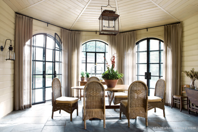 The new sunroom provides a bridge from the main house to an elegant outdoor pool area. The antique table is surrounded by wicker chairs by Mainly Baskets.