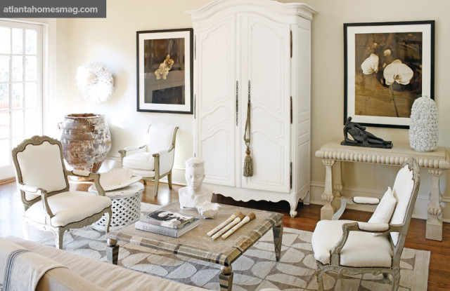 In the family room, classic pieces, like the 18th-century French chairs and 19th-century French armoire, are interspersed with a David Roper cocktail table, Joseph Guay photography, a Greek olive jar, even an African ceremonial headdress—the combination grounded by a modern flat-weave rug. French chairs, Tom Hayes & Associates. Armoire, Anne Flaire Antiques. Rug, Moattar, Ltd.