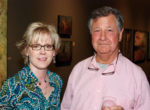 Woman with blonde hair and glasses wearing a blue and green patterned shirt, and a man with graying hair wearing a pink striped shirt and glasses around his neck.
