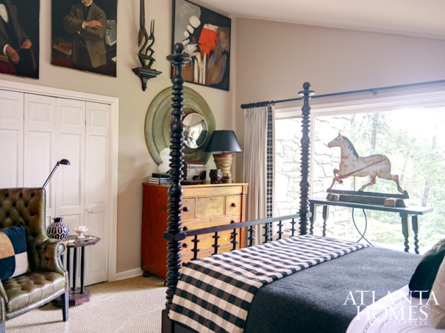 Eddie Alvarez and George Oliver envisioned the main home's guest bedroom as a stylish and relaxing retreat after a day of horseback riding on this sprawling property. An antique horse weathervane used as a sculpture, lamps made from antique English riding boot forms and a set of 18th-century German horse engravings contribute to its equestrian flair. The walls and sloped ceiling were painted the same hue to create the illusion of height. Custom cabinetry in the bathroom is by Kindgom Woodworks.
