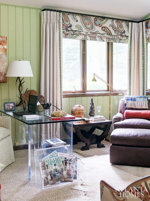 In the study/sitting room, she and Dennis Schuhart desired to level the space and create a more pleasing proportion. A Travis acrylic desk with a glass top blends into the room, which also boasts a low side table and a club chair and ottoman upholstered in Romo/Kirkby Design's Chester Hide. Mixed media pieces from Pryor Fine Art join antique and wooden accessories. The Cowtan & Tout paisley fabric on the roman shade also covers the 1930s Bergere, which sits on a calfskin rug and next to a custom desk chair by Travis.
