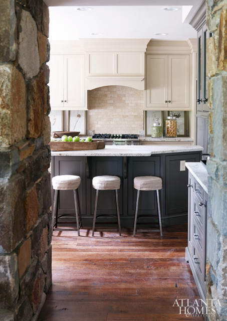 The kitchen was designed by Kathleen Rivers, whose cabinetry layout made the small, angled space feel larger, Amy Morris says, while neutral paint lightened up the room. The dark island anchored the space, with stools from Arteriors. Morris used hardware from Top Knobs, fixtures from Circa Lighting and assorted window treatments, art and decorative objects. The kitchen extended to the porch, where iron chairs and a cast-concrete table designed to withstand the elements contrasted with the wood.