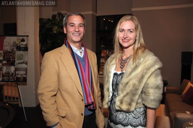 Man in tan blazer and striped scarf smiles next to a woman wearing a fur stole and ornate necklace.
