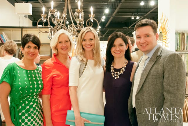 Five people pose for a photo in front of a chandelier and shelves stocked with fabric samples. The Atlanta Homes & Lifestyles logo is visible in the lower right corner.
