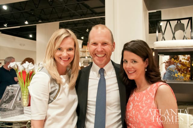 Three smiling people, two women and one man, pose for a photo. Books titled "Paris in the 1920s" are visible on a table to the left. The Atlanta Homes & Lifestyles logo is visible on the right.
