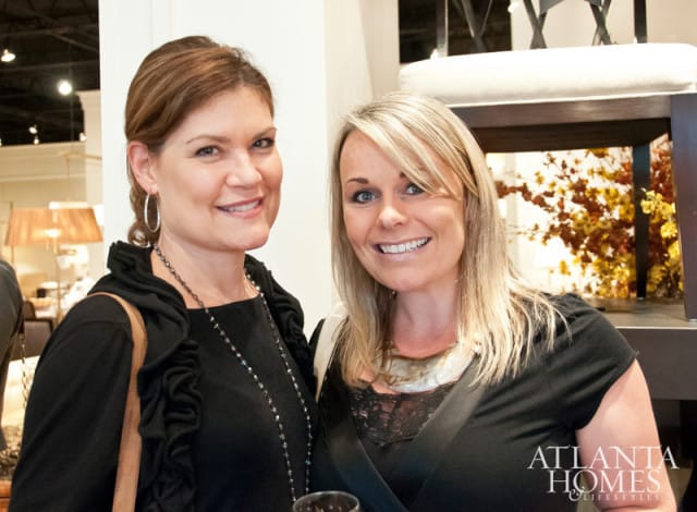 Two women smiling, one with brown hair and hoop earrings, the other with blonde hair.