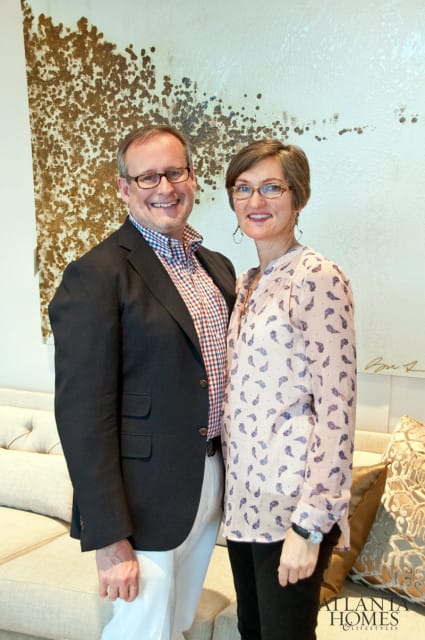 Steve and Jill McKenzie standing in front of a textured wall art and a tufted sofa.