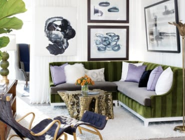 Living room with a green striped sectional sofa, gold metallic tree stump coffee table, abstract art, and woven chairs.