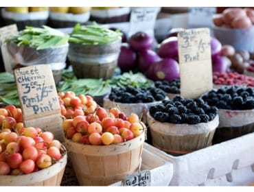 Baskets of fresh cherries and blackberries for sale at a market, with signs indicating prices per pint.