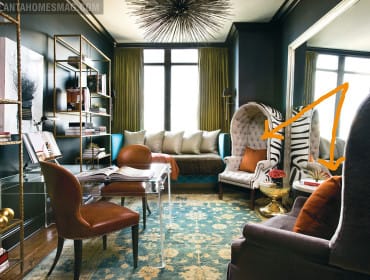 Dark teal room with a clear desk, brown leather chairs, a tufted daybed with white pillows, and a high-backed chair upholstered in zebra print fabric.